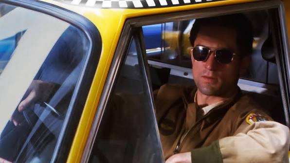 Close-up of Robert De Niro as Travis Bickle in Taxi Driver 1976, looking out of a taxi window with a gaze of intense hatred at the neon-lit New York street grime
