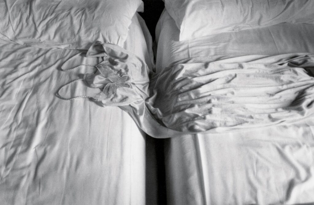 An unmade bed in a hotel room, symbolizing absence in Sophie Calle's art.